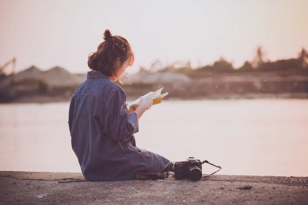 mulher asiática lendo a beira de um lago.