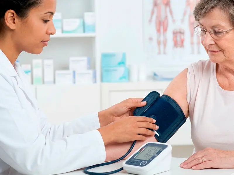 uma profissional da saúde aferindo a pressão de uma mulher idosa